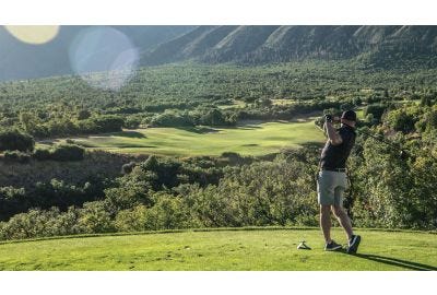 Golfer on a golf course hitting a golf ball down the green.